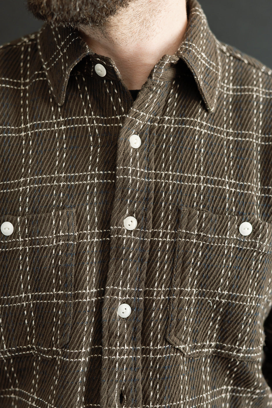 Close-up front view of a brown plaid flannel shirt showing button details and fabric texture.