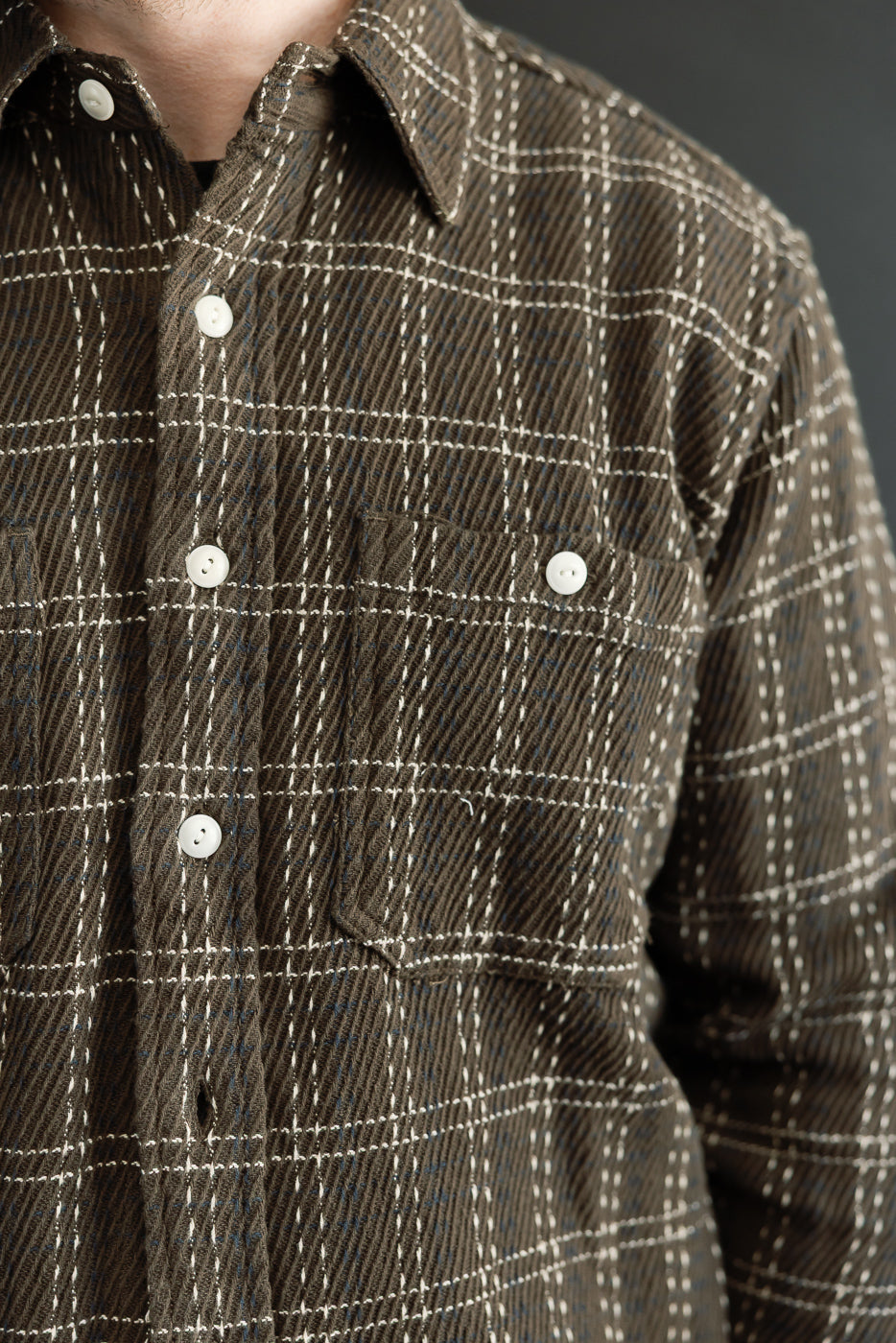 Close-up front view of a brown plaid corduroy button-down shirt showing fabric texture and pocket.
