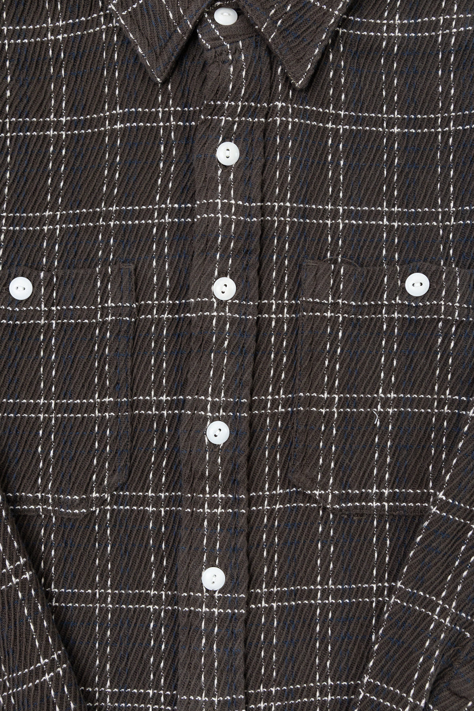 Close-up front view of a dark brown plaid button-down shirt showing white buttons and fabric texture.