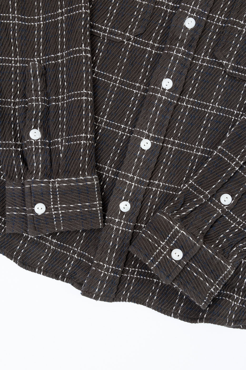 Close-up front view of dark brown plaid flannel shirt showing fabric texture and white buttons.