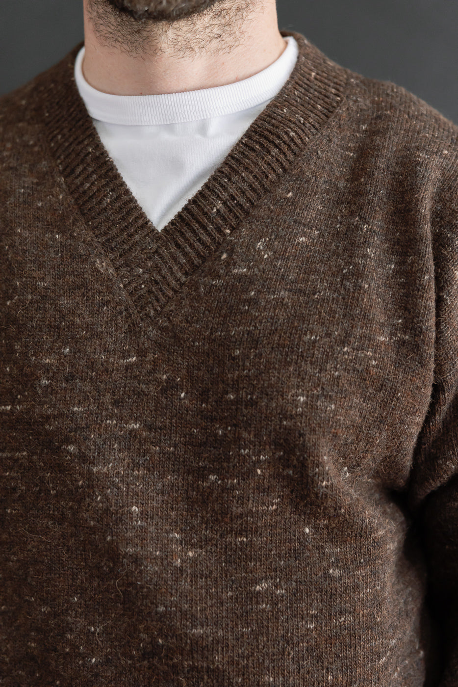Close-up front view of a brown v-neck knit sweater on a male model, 5'9