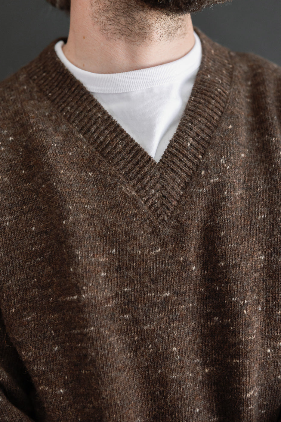 Close-up front view of a brown v-neck sweater on a male model, 5'9