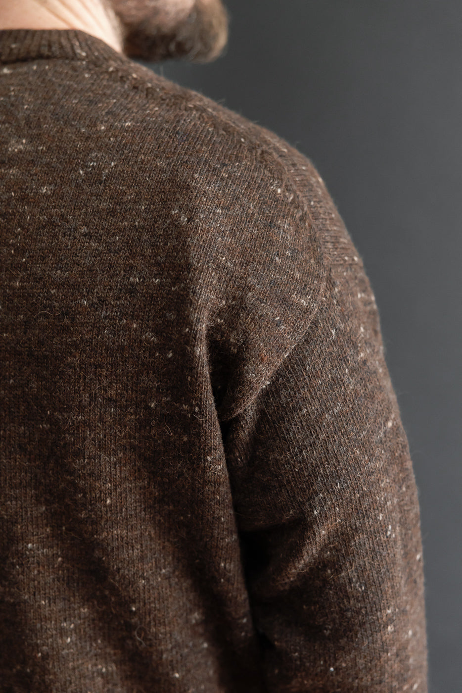 Close-up of the back and shoulder area of a brown textured knit sweater.