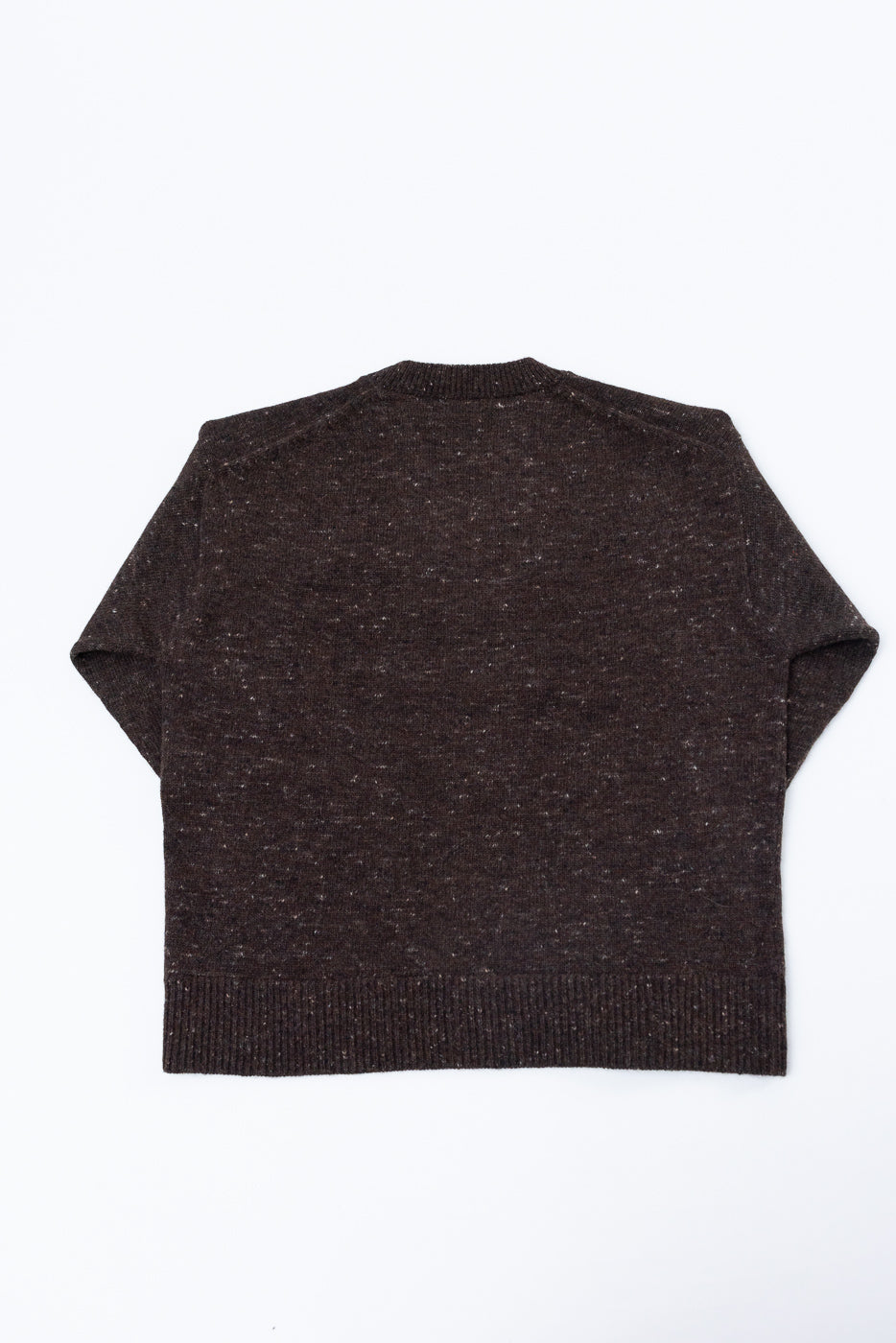 Flat lay of the back of a dark brown speckled knit sweater with a ribbed hem.