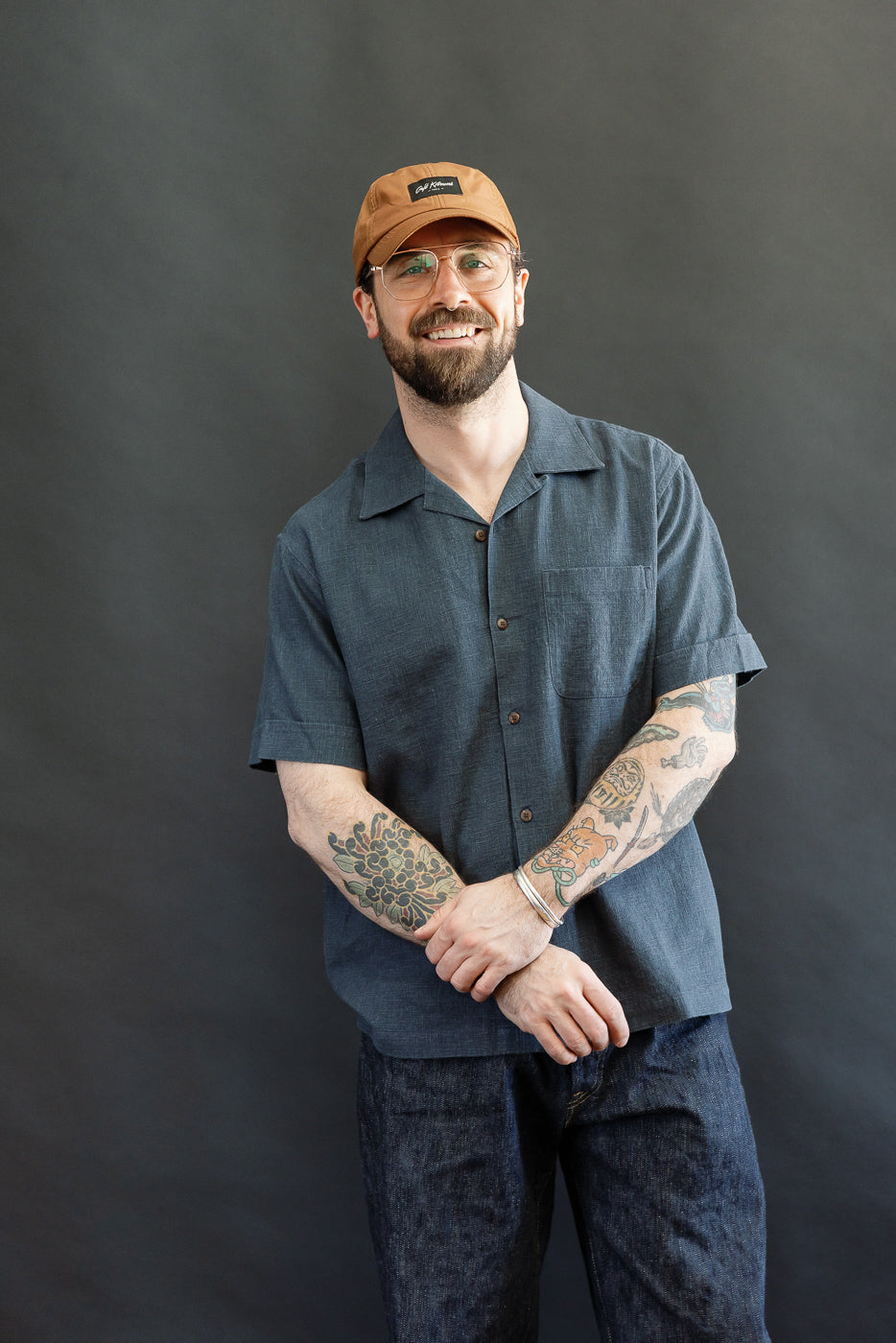 Man wearing the Vacation Shirt - Blue Linen, a short-sleeved, button-up with an open collar, showcasing its relaxed fit and single chest pocket. The shirt's soft linen texture and coconut buttons are visible.