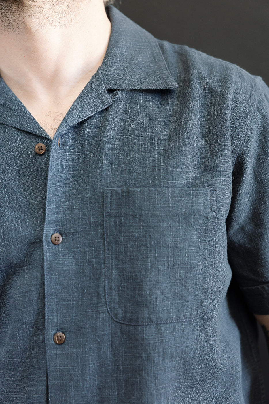 Person wearing the 3sixteen Vacation Shirt - Blue Linen, featuring a camp-style collar, textured fabric, and brown coconut buttons, highlighting the relaxed, modern fit inspired by 1950s leisure shirts.