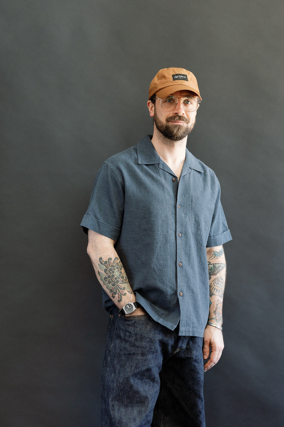 Model wearing the 3sixteen Vacation Shirt in blue linen, showcasing its open-collar design, buttoned-up style, and single chest pocket, reflecting a modern update to 1950s leisure shirts.