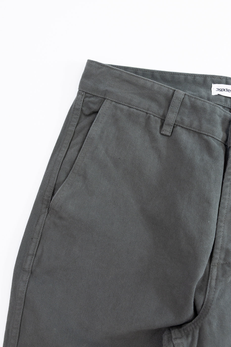 Close-up of gray pants with a brand label on a white background