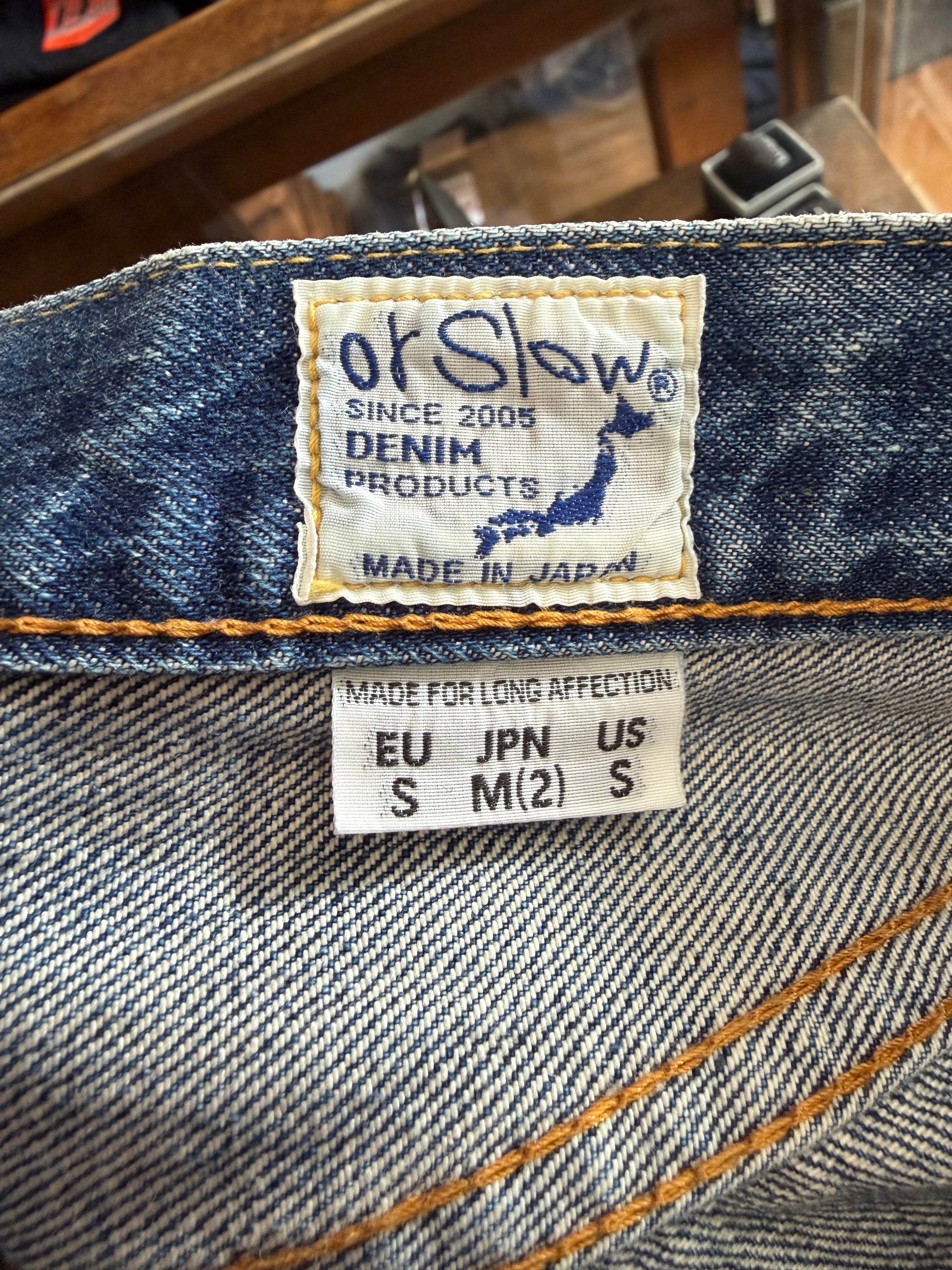 Close-up of orSlow denim jeans inner waistband showing stitched brand tag and size label, front view.