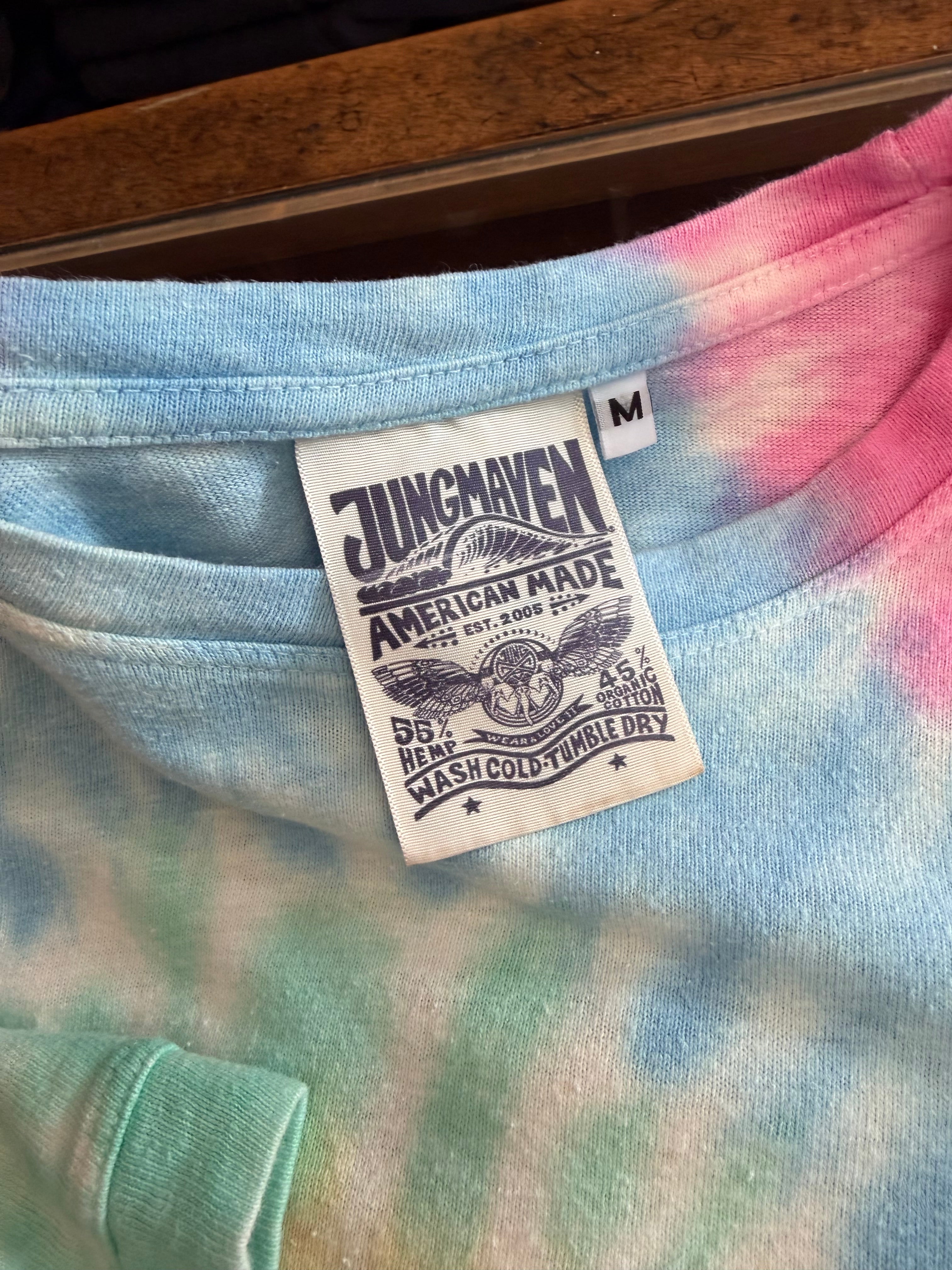 Close-up of tie-dye t-shirt neck tag showing Jungmaven brand, hemp-cotton blend, size M, care instructions