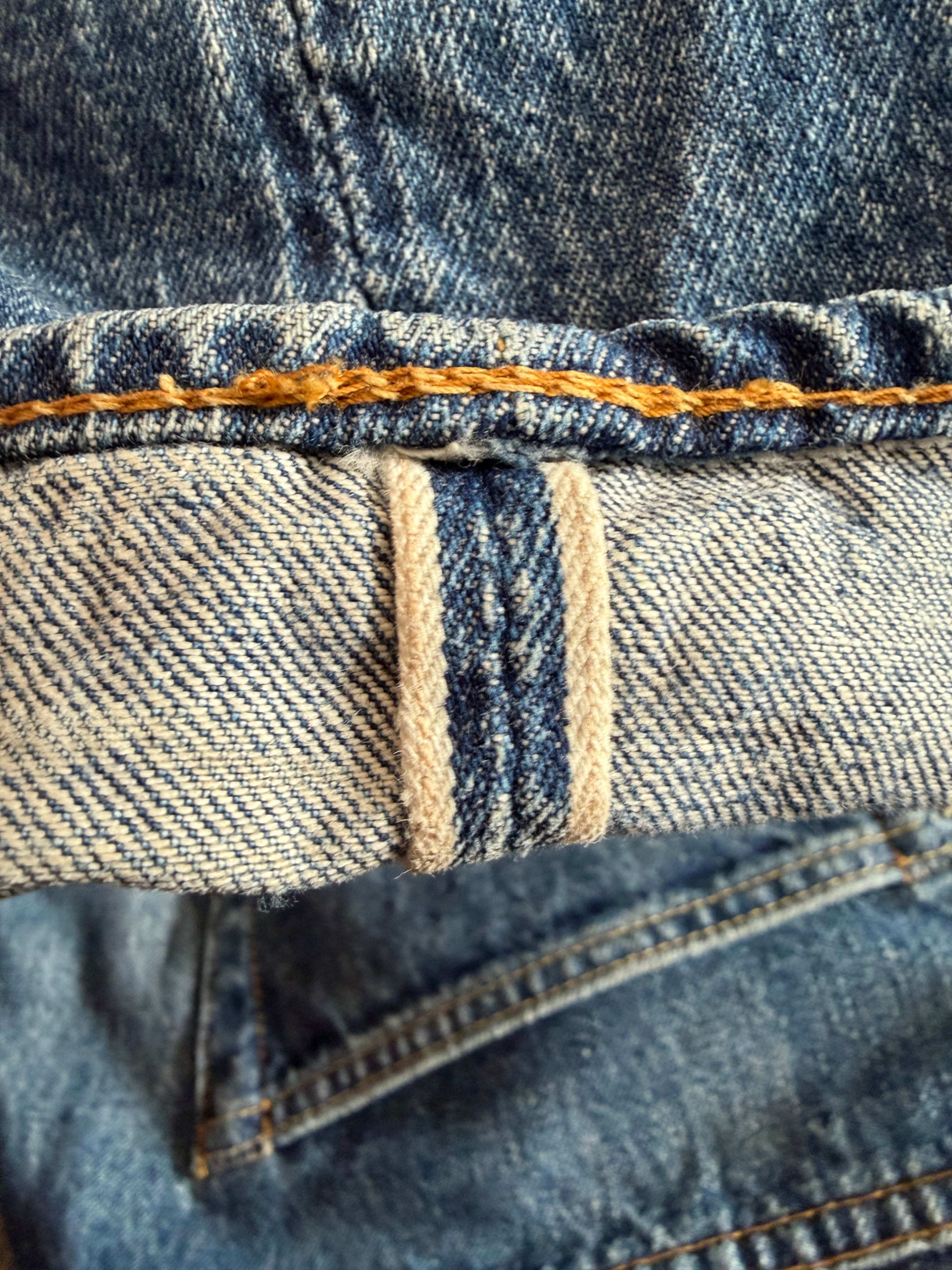 Close-up of selvedge denim cuff, visible stitching detail and texture, front view.