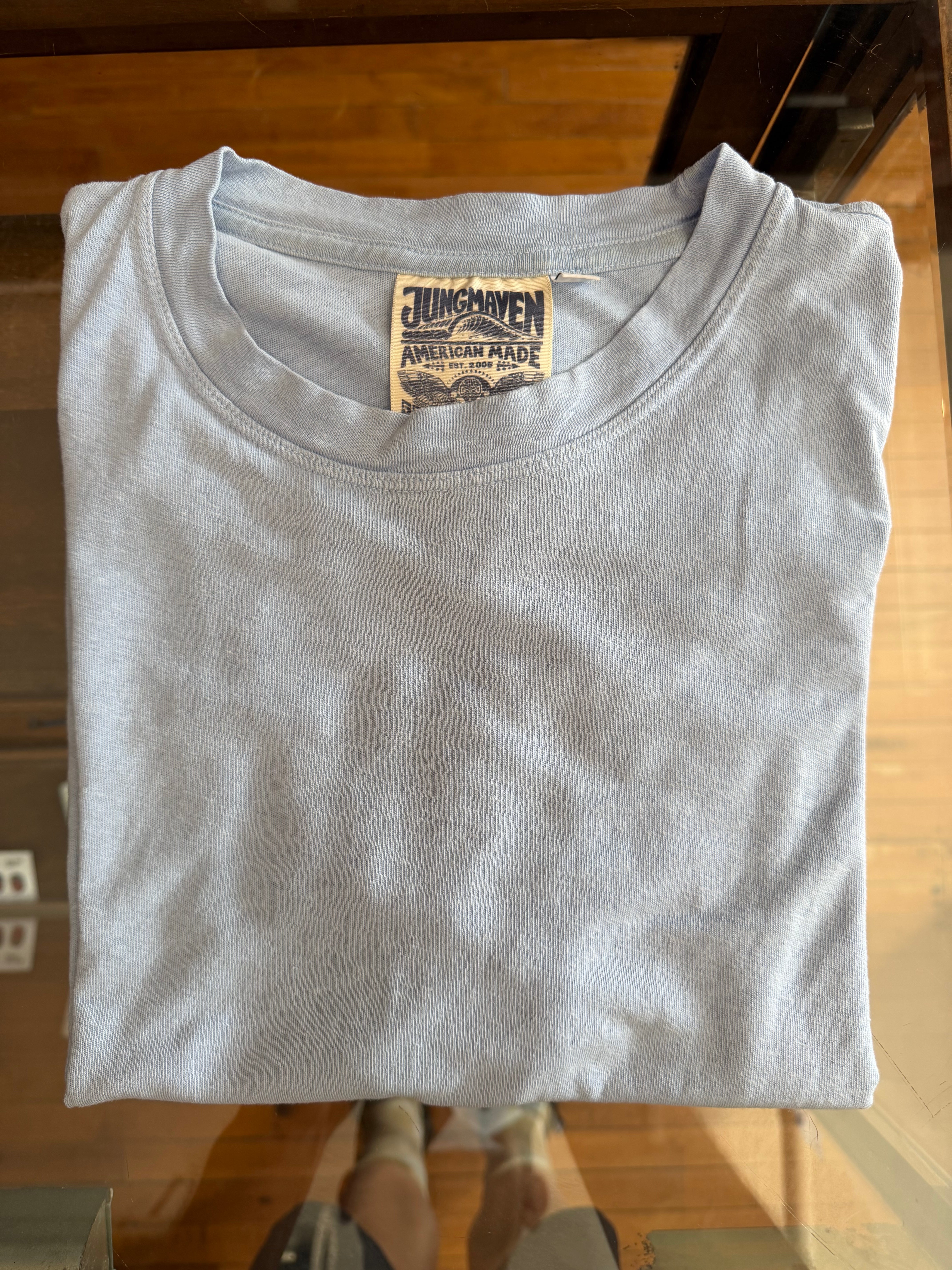 Folded light gray t-shirt, front view, showing Jungmaven tag with American Made design.
