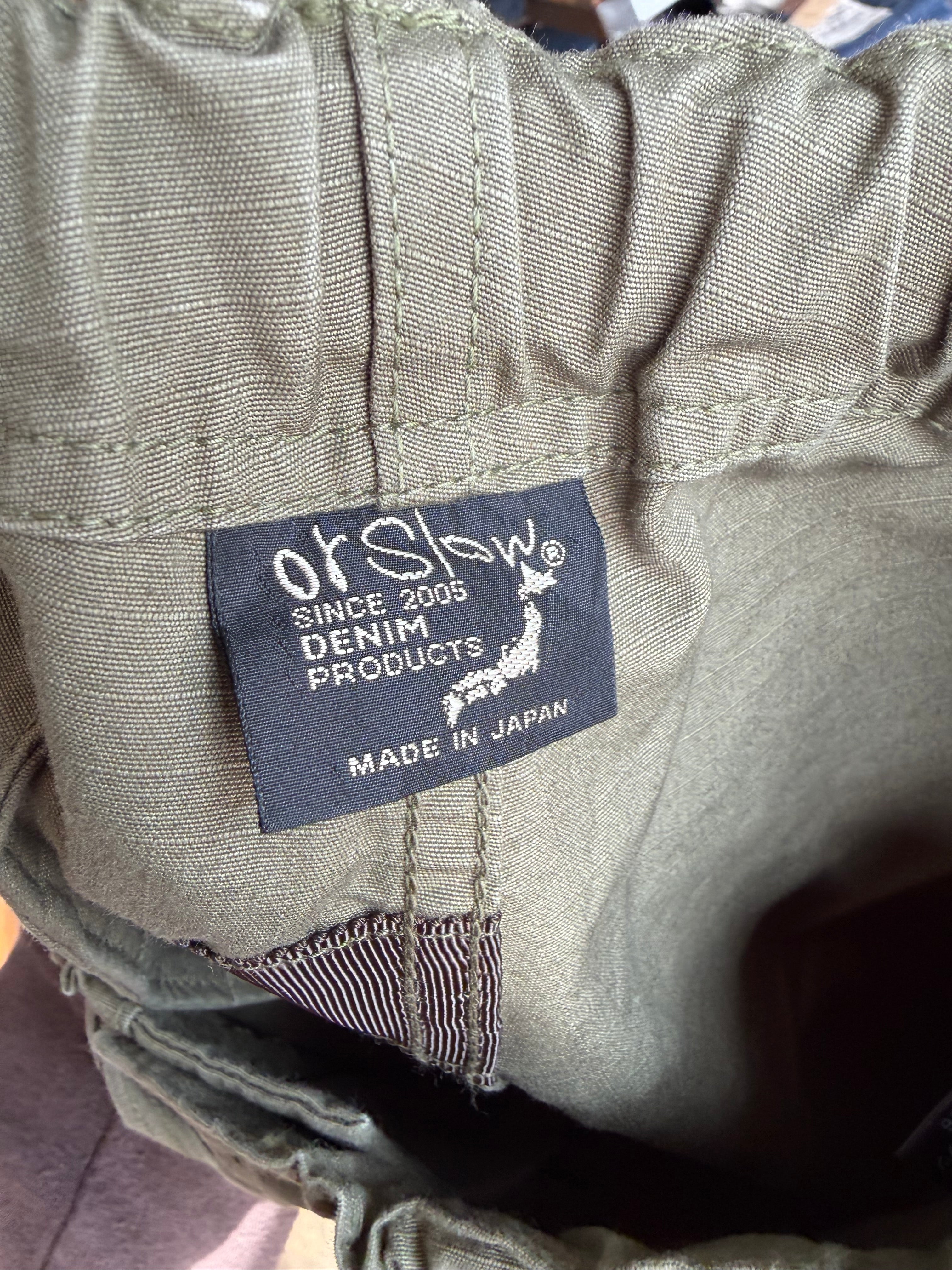 Close-up of orSlow denim pants interior waist tag, khaki fabric texture, front inside view.