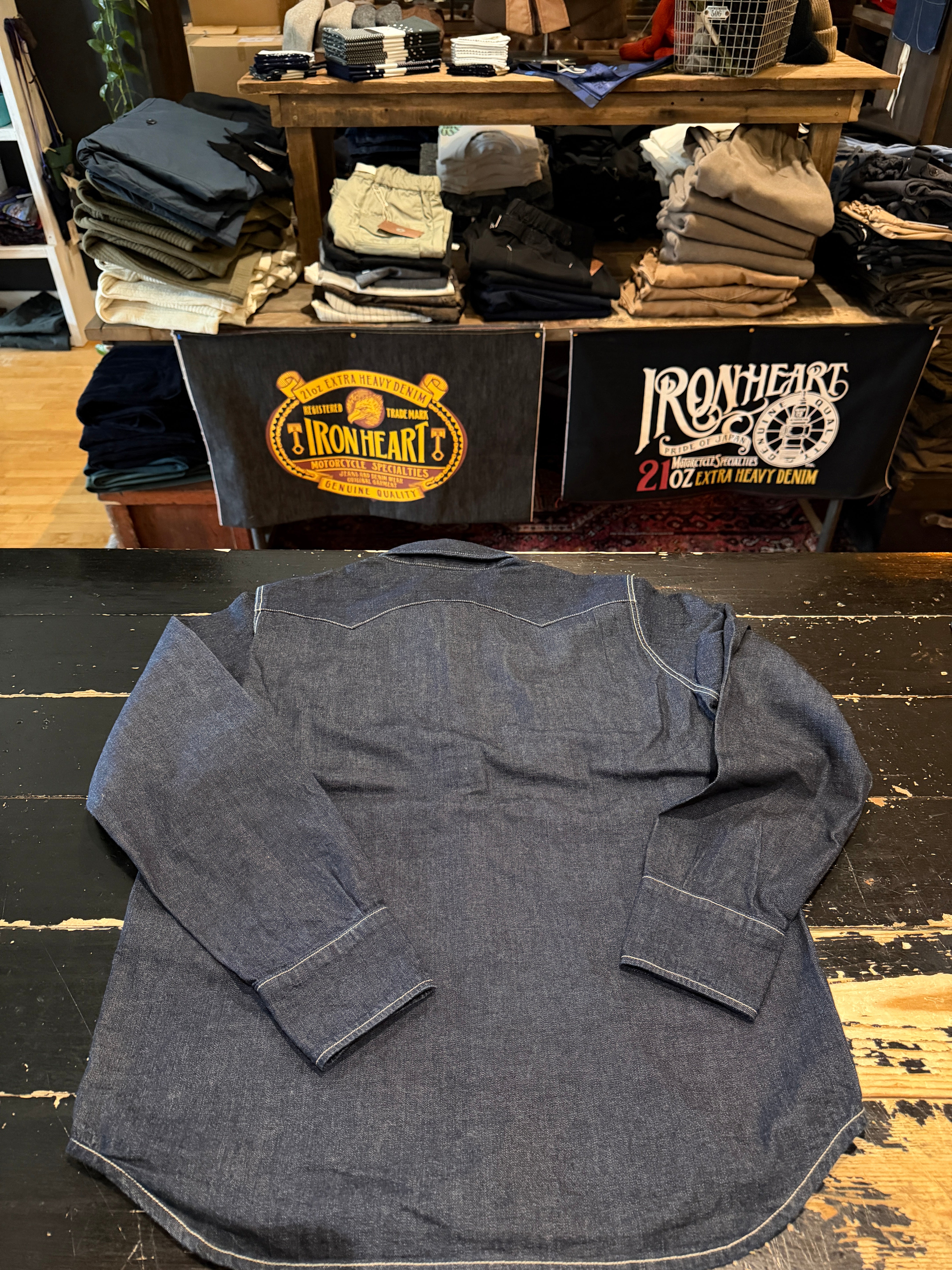 Flat lay of a long sleeve denim shirt, back side visible, showing cuff and yoke details.