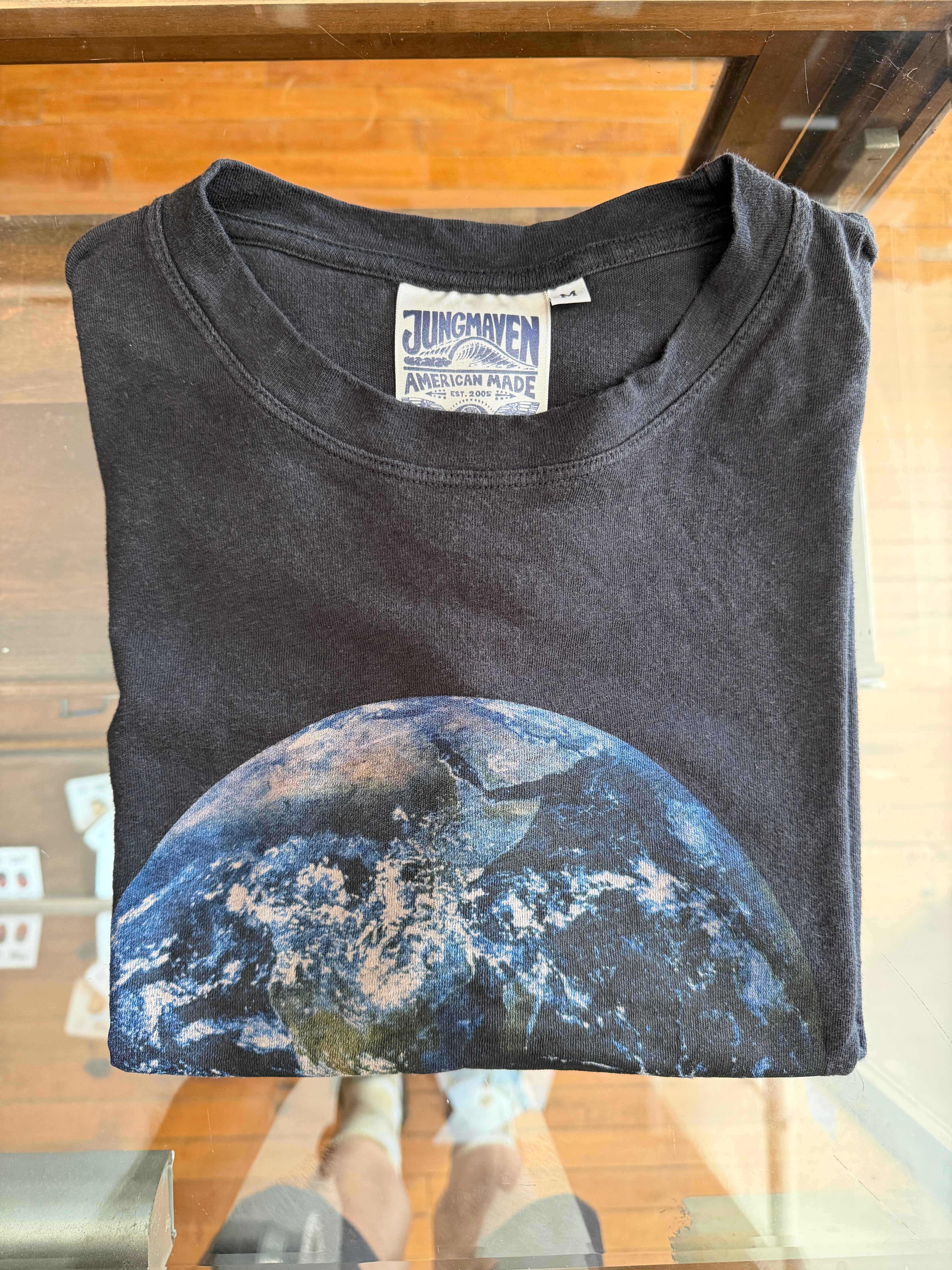 Front view of black t-shirt with Earth graphic, Jungmaven tag visible, folded on display