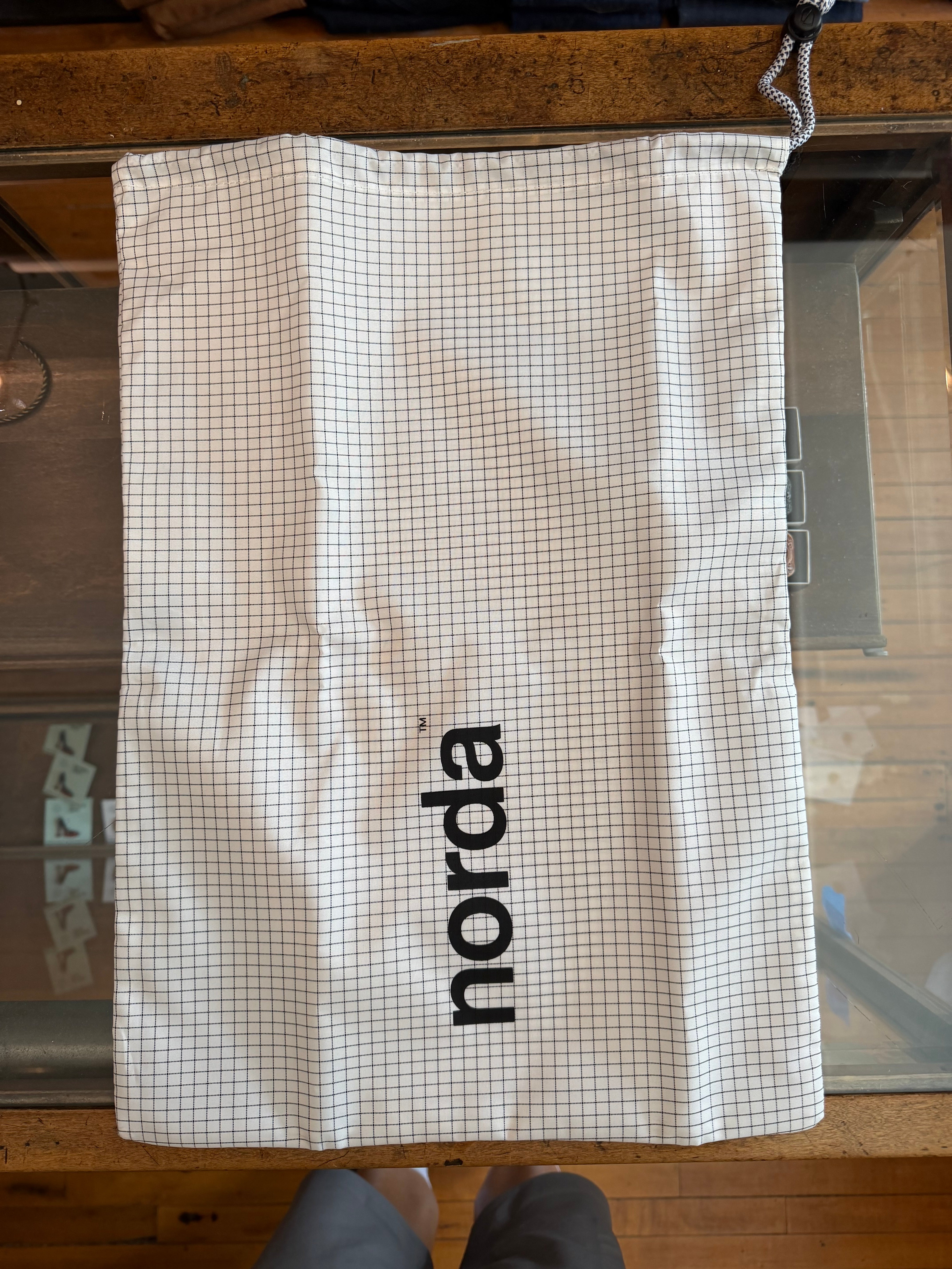 Norda drawstring bag with grid pattern, front view, displayed on wooden surface
