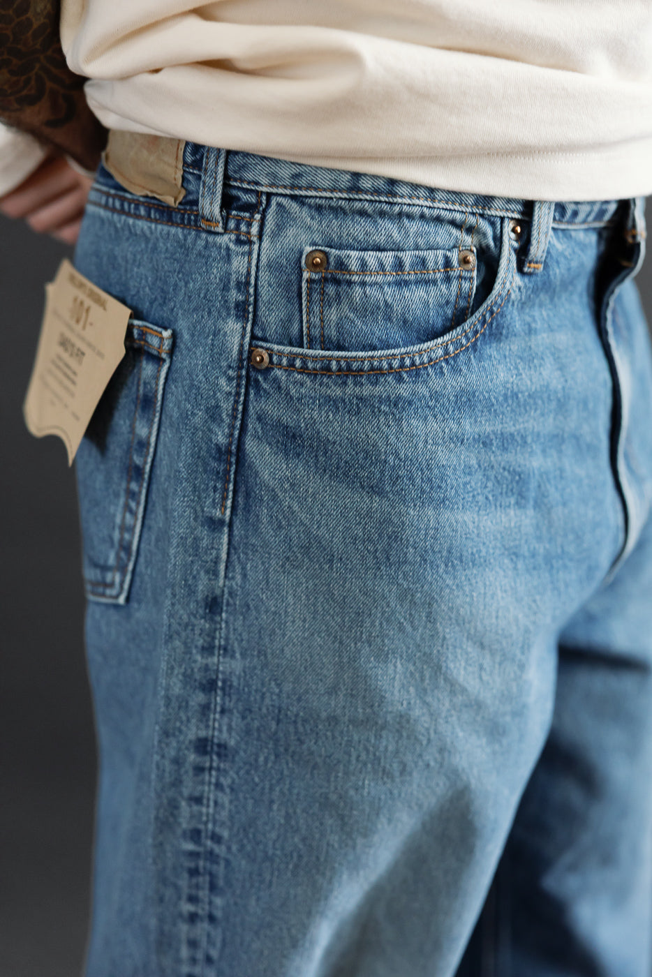Close-up side view of light wash denim jeans on a male model, 5'9