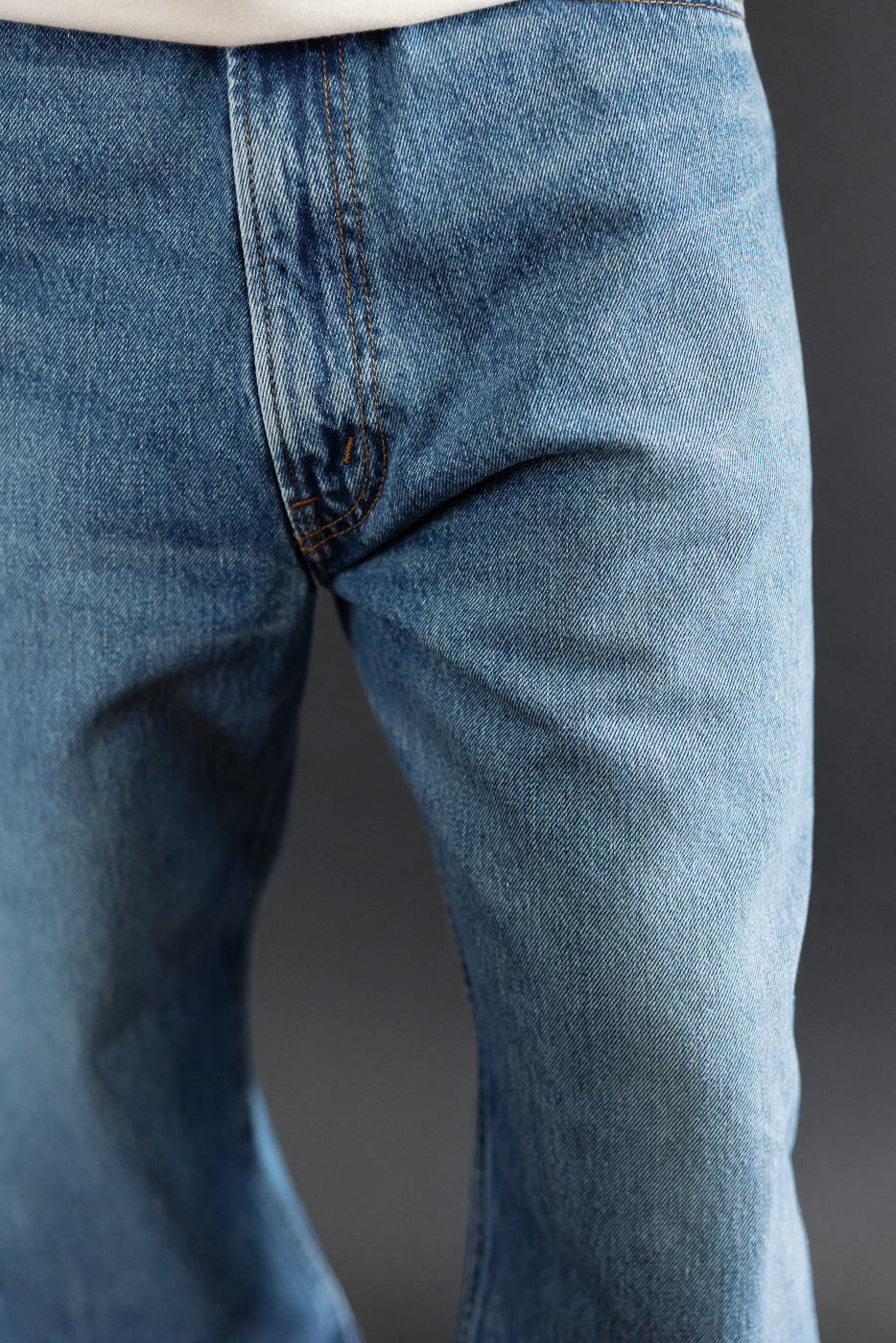 Close-up of the front fly and waistband of blue selvedge denim jeans.