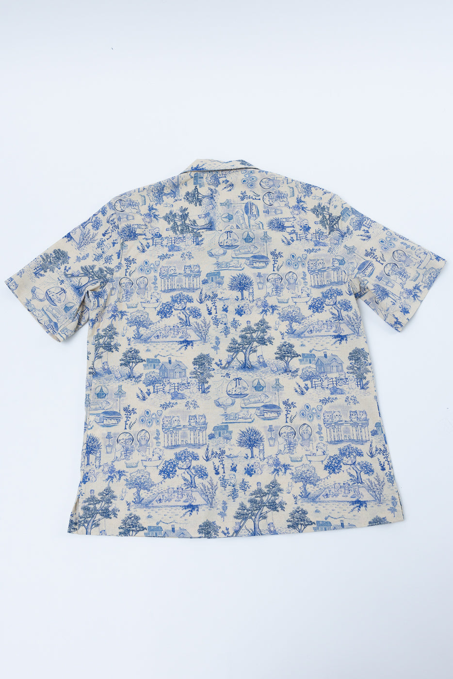 Flat lay, back of linen aloha shirt in blue cat print, short sleeves, straight hem visible.
