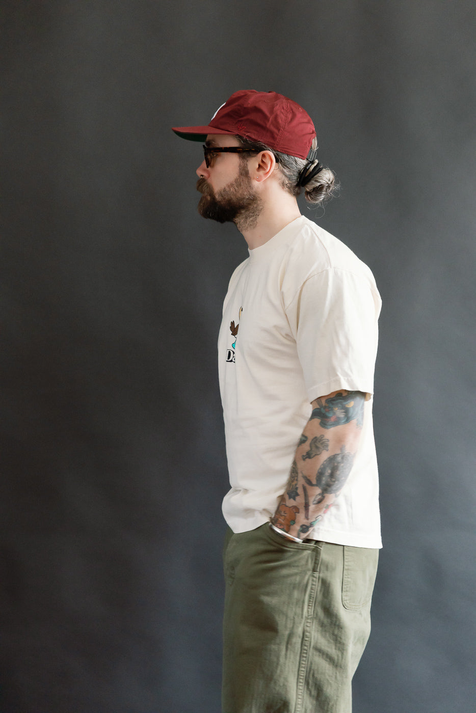 Man in profile wears 6.5oz - Dant Blue Footed Booby T-Shirt - Ecru, showcasing its oversized fit and bird graphic, embodying Dant's heritage-inspired style with modern flair.