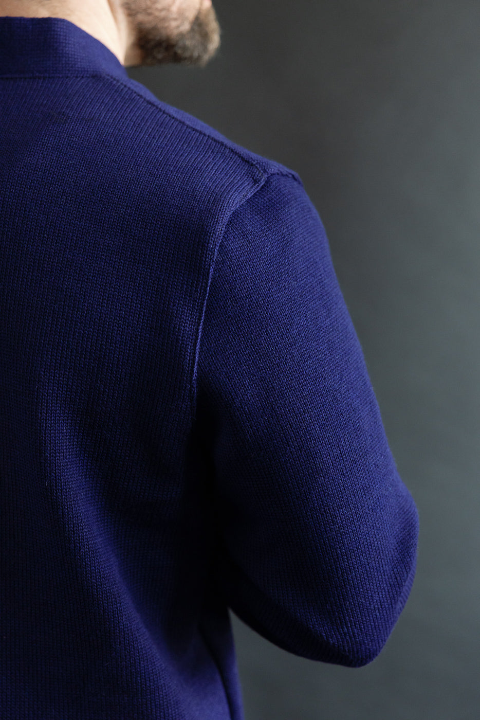 Close-up of left shoulder and sleeve detail, classic purple cardigan on male model, back view.