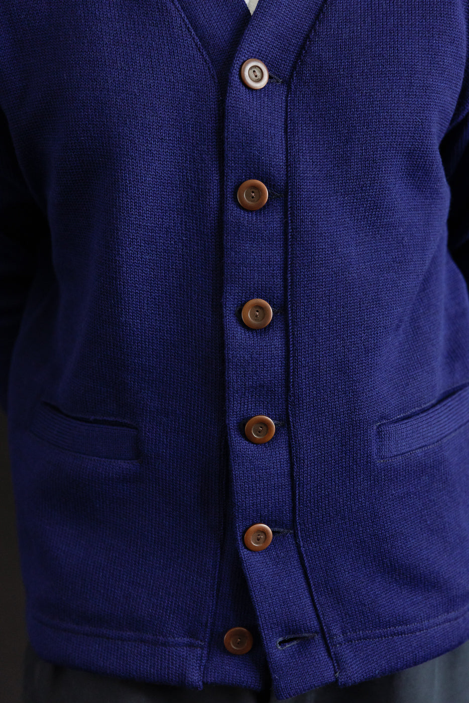 Close-up of men's classic purple cardigan front, brown buttons, textured knit, front pockets.
