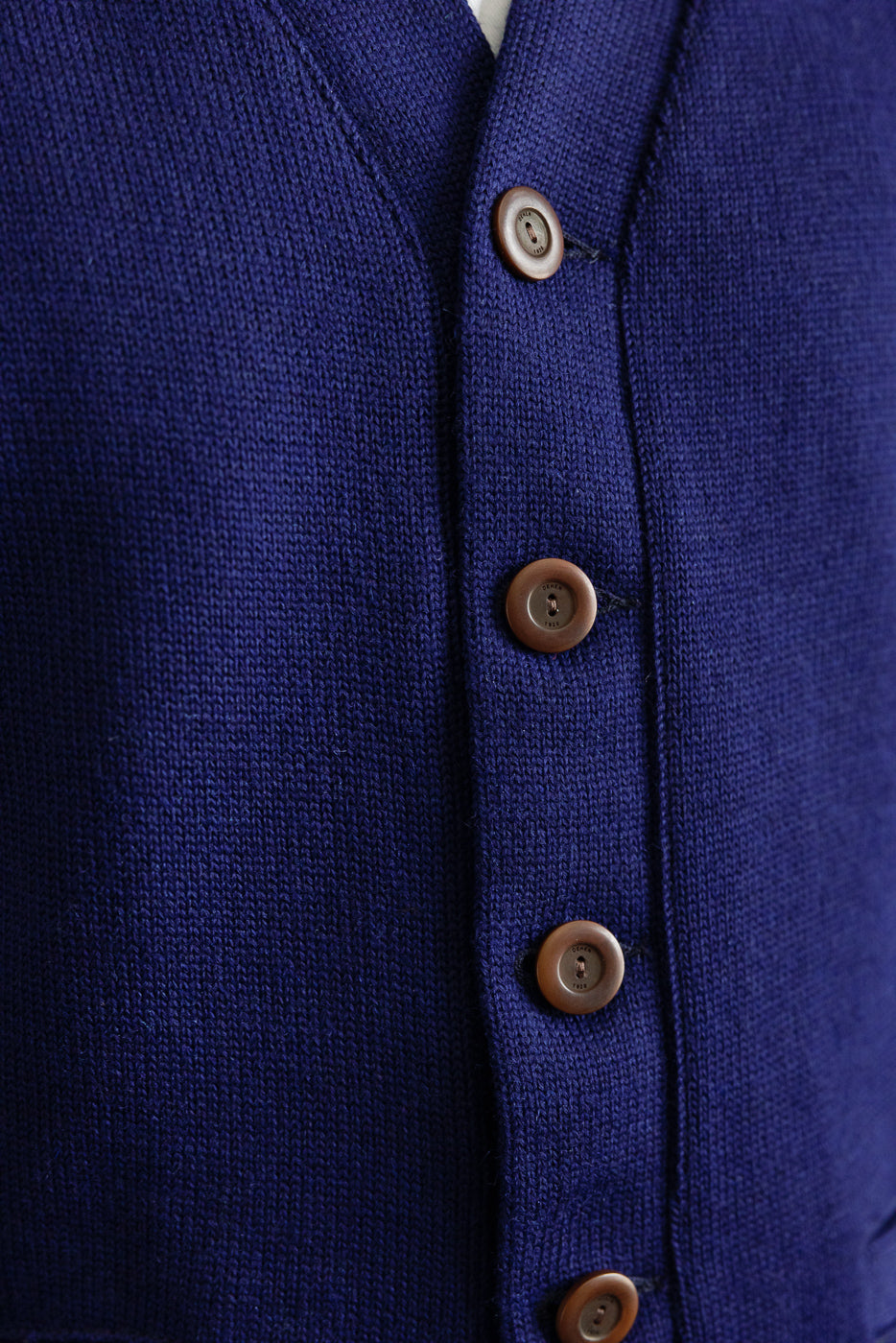 Close-up of front button placket on purple knit classic cardigan showcasing brown buttons and textured fabric.