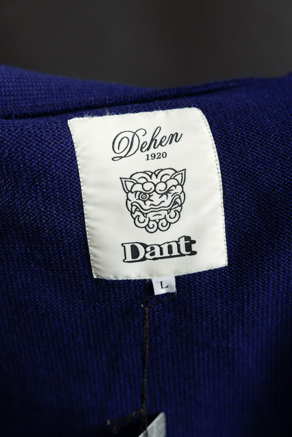 Close-up of inner neck label on classic purple cardigan, showing tag details and knit texture.