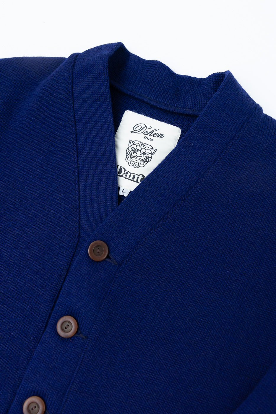 Close-up of front upper section of purple cardigan, showing v-neck collar, brown buttons, and fabric texture.