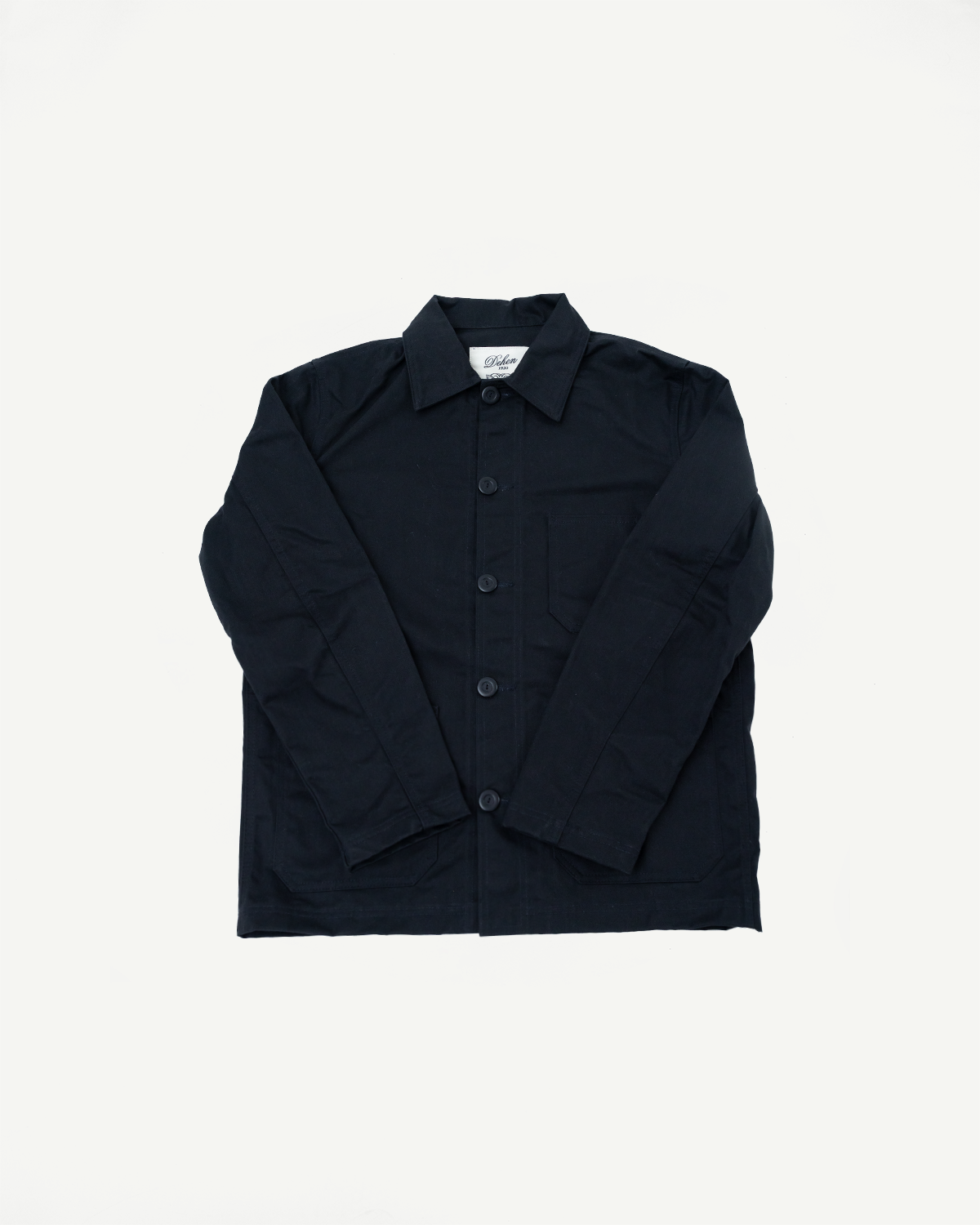 Flat lay front view of black dry wax woven chore coat, showing collar, buttons, chest pocket.