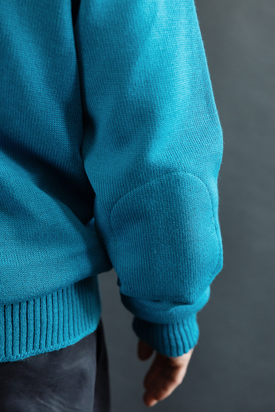 Close-up of male model's right sleeve and elbow detail on aqua moto hoodie, athletic build.