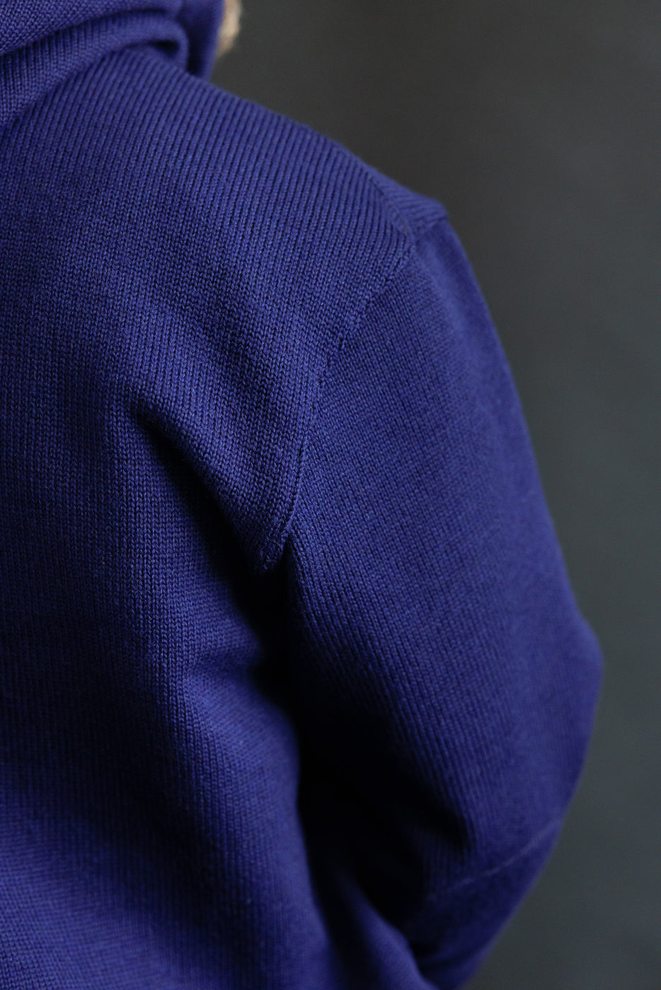 Close-up of male model’s left shoulder in purple moto hoodie, showing knit fabric texture.