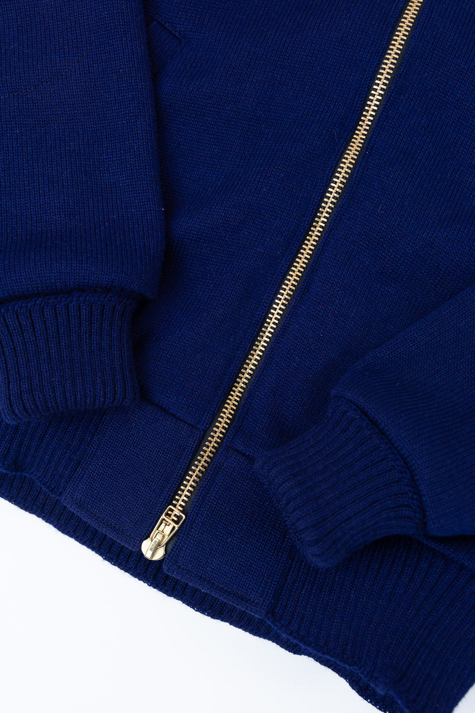 Close-up of front lower section of purple moto hoodie showing gold zipper and ribbed cuffs.