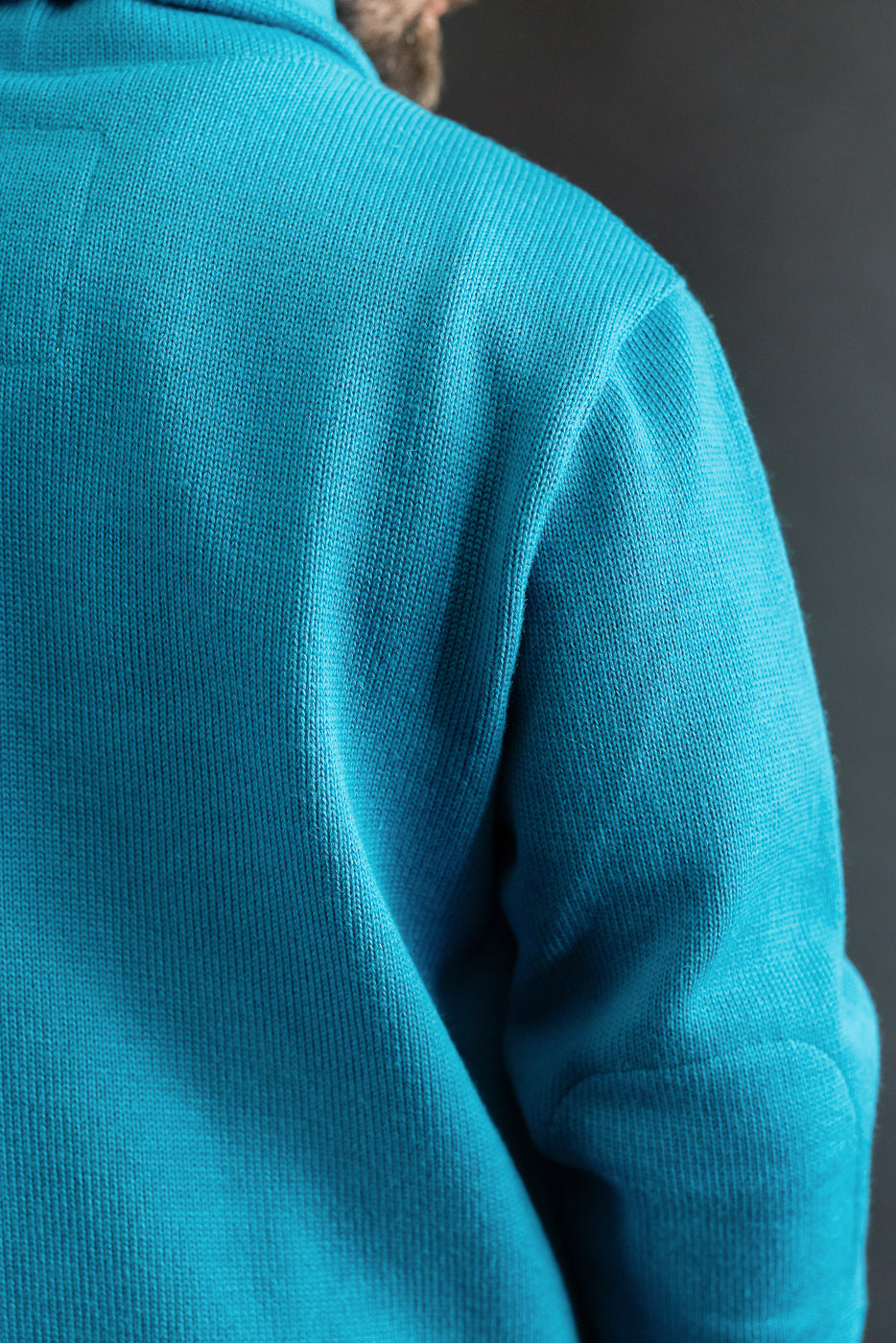 Close-up of male model's back in aqua shawl sweater coat, highlighting knit texture