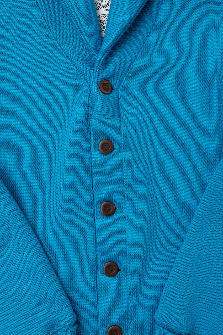 Close-up of front buttons and shawl collar on aqua blue sweater coat, showing knit texture.