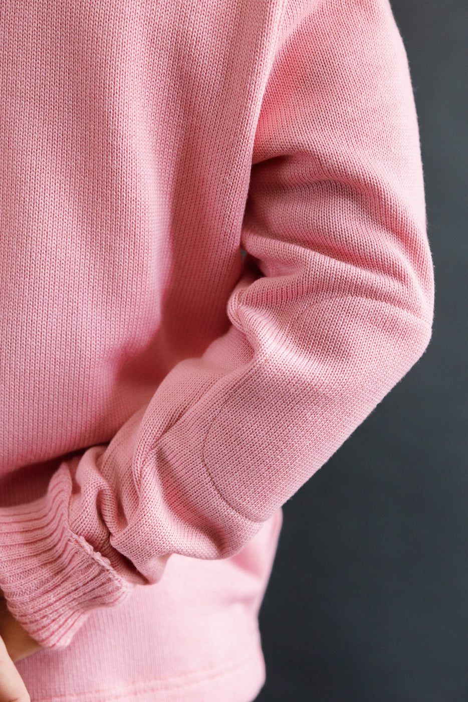 Close-up of left sleeve and elbow patch on men's bubblegum pink shawl sweater, ribbed cuff detail.