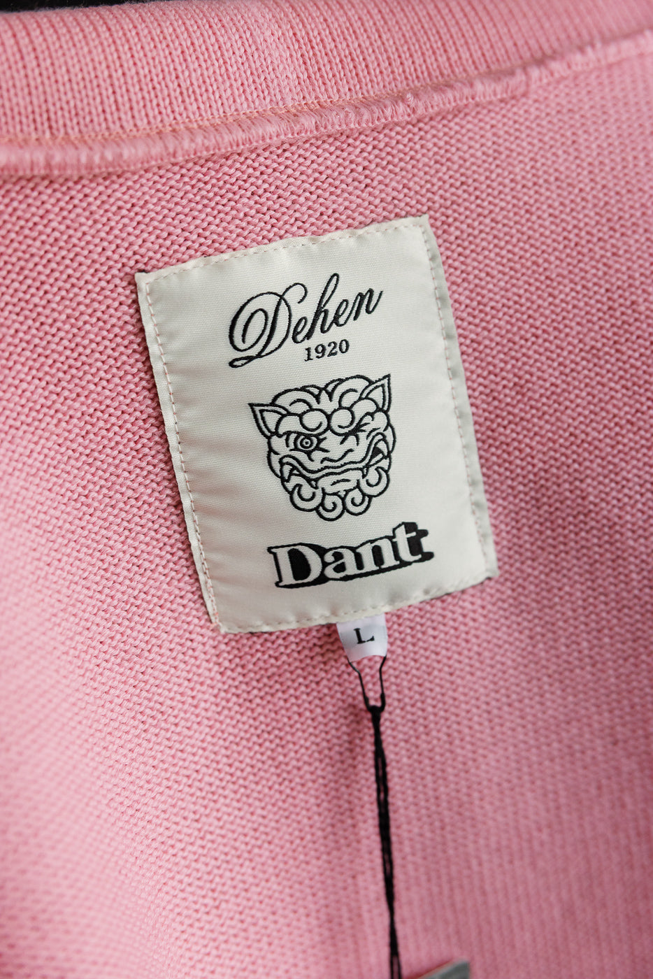 Close-up of inside neck area, bubblegum pink knit shawl sweater coat, showing fabric texture and woven brand tag, back view.