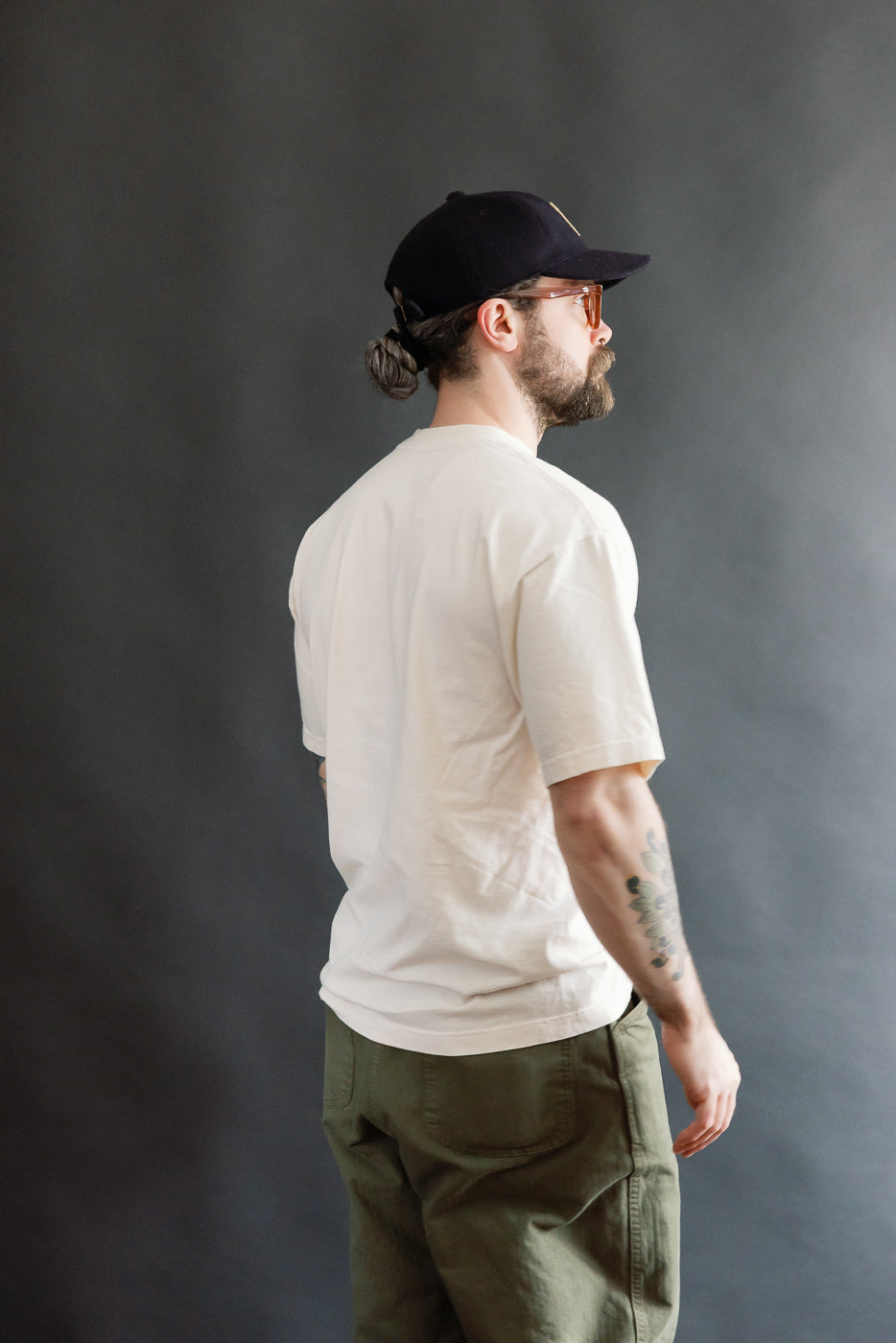 Model wearing the 6.5oz Dant Northern Flicker T-Shirt in Ecru, featuring the bird design, showcasing the shirt's oversized fit. Styled with olive-green trousers, capturing Dant's heritage-inspired aesthetic.