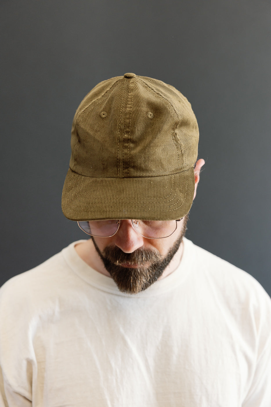 Man wearing Corduroy Baseball Hat - Olive with a neatly trimmed beard. The soft, thin-wale corduroy and 6-panel unstructured crown lend a classic, refined touch, enhanced by a leather strap and brass hardware.