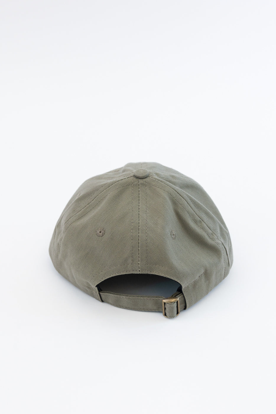 Dehen’s Dry Wax Cotton Baseball Hat in Sage features a six-panel design with tonal eyelets, an adjustable self-fabric strap, and a brass slider, showcasing its unstructured elegance and heritage craftsmanship.