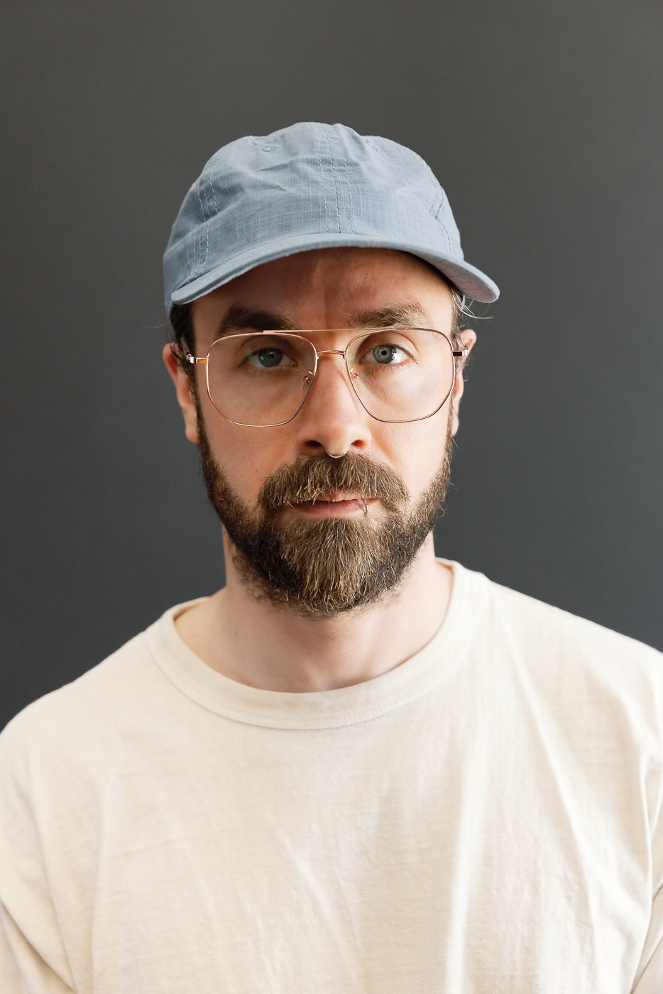 Front close-up of faded blue ripstop cotton baseball hat on male model, 5'9, 165lbs, athletic build