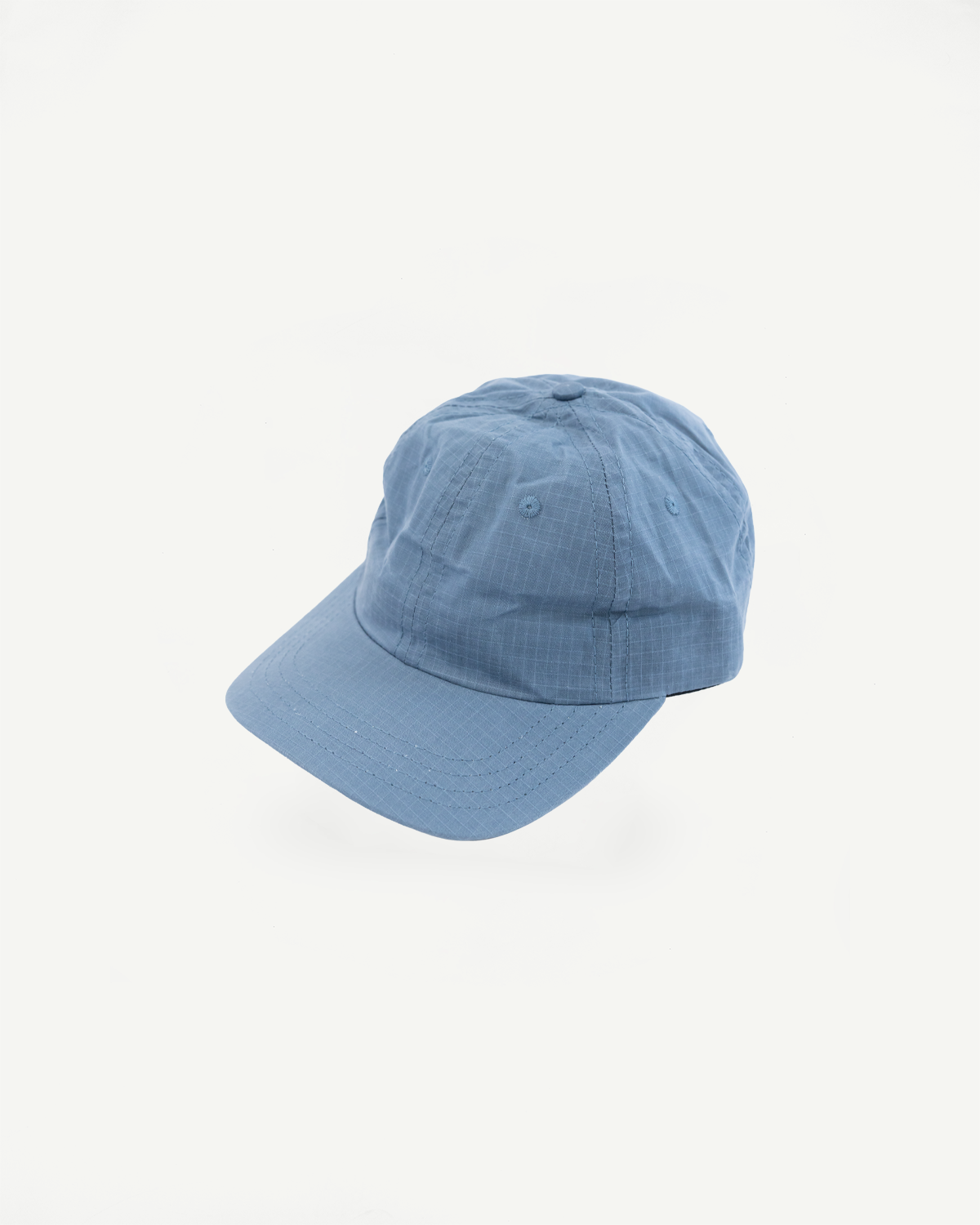 Front flat lay of faded blue ripstop cotton baseball hat, showing structured crown, curved brim and visible ventilation eyelets.