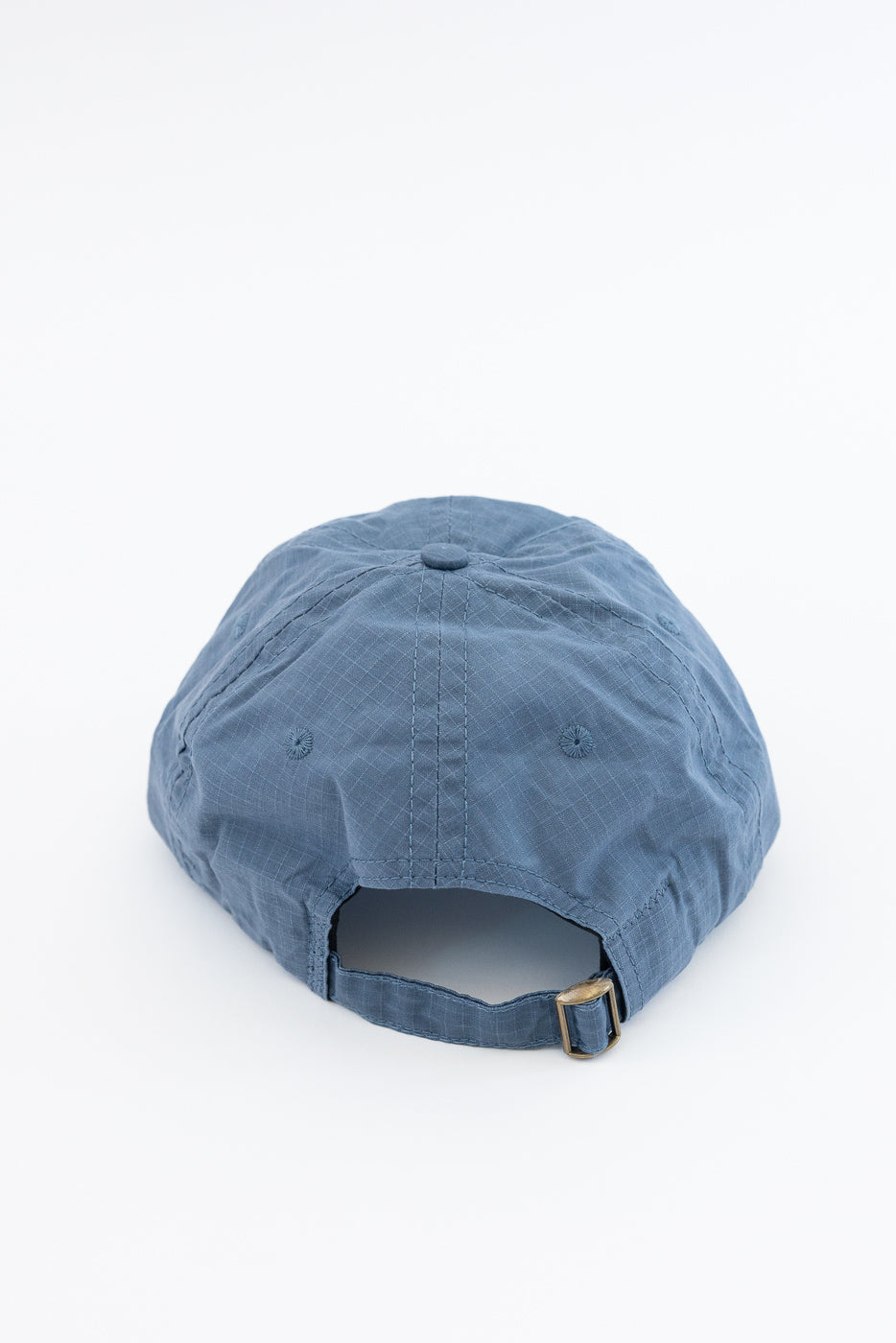 Close-up of back of faded blue ripstop cotton baseball hat, adjustable strap detail visible.