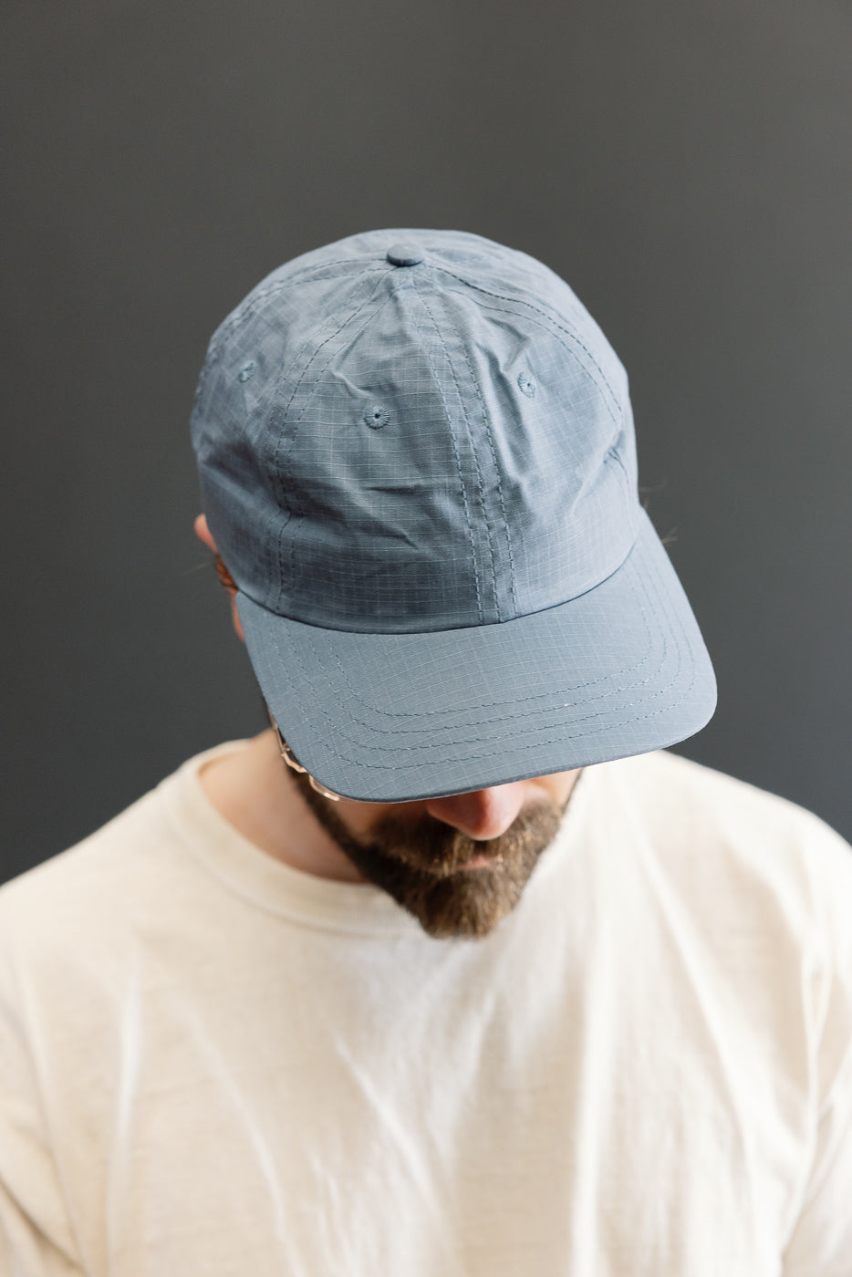 Close-up front view of faded blue ripstop cotton baseball hat on male model, 5'9