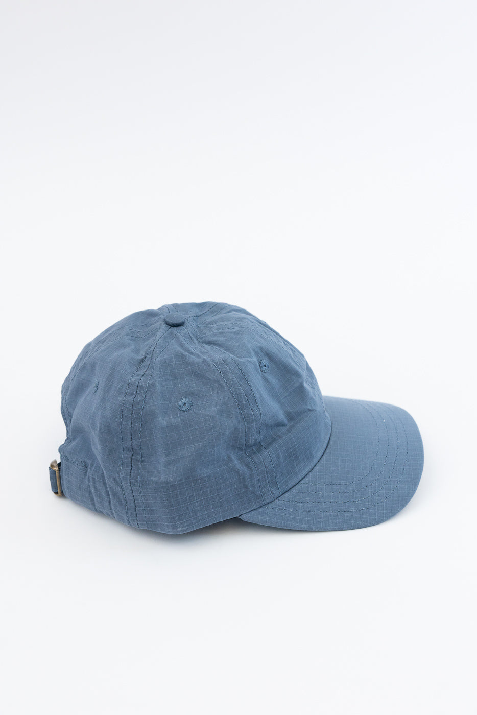 Close-up of back and side of faded blue ripstop cotton baseball hat with adjustable strap