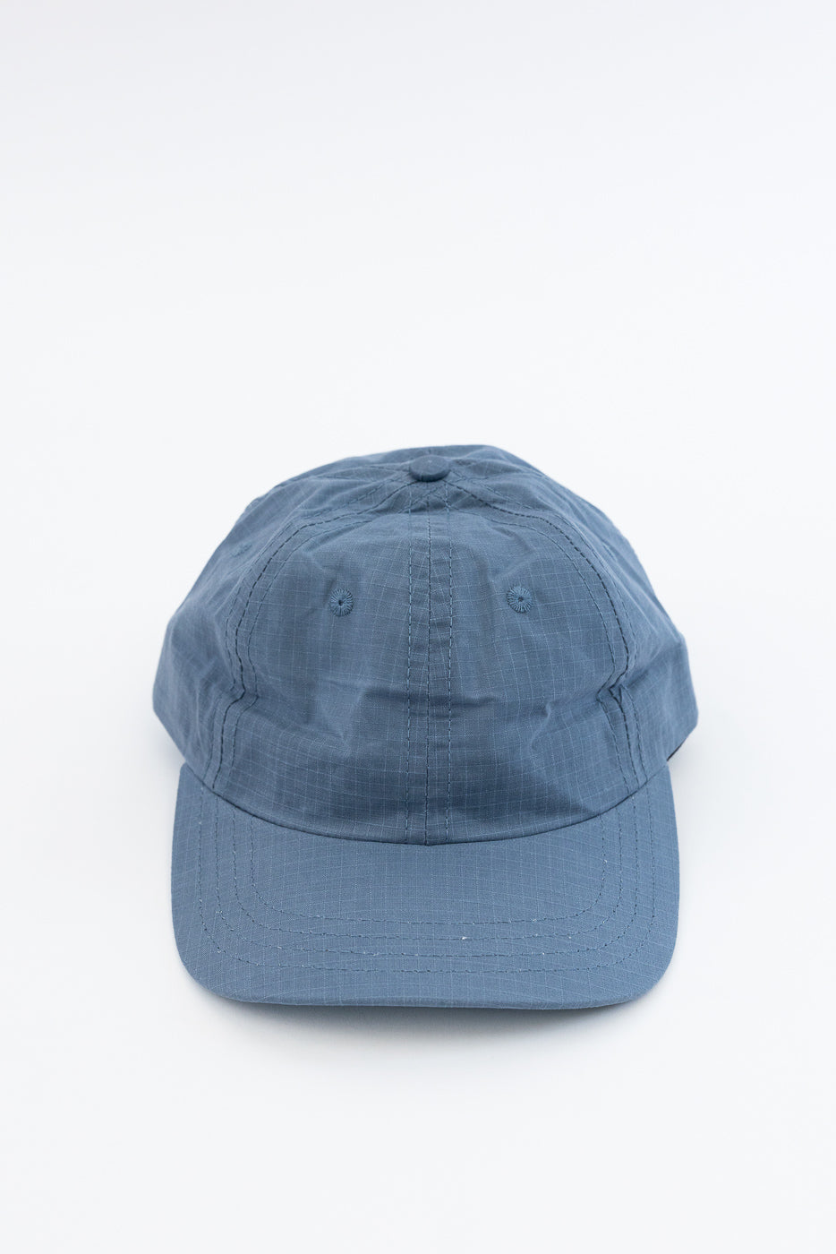 Front view close-up of faded blue ripstop cotton baseball hat, showing crown and brim details.