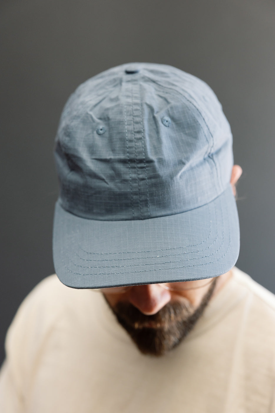 Close-up front view of a faded blue ripstop cotton baseball hat on male model, 5'9