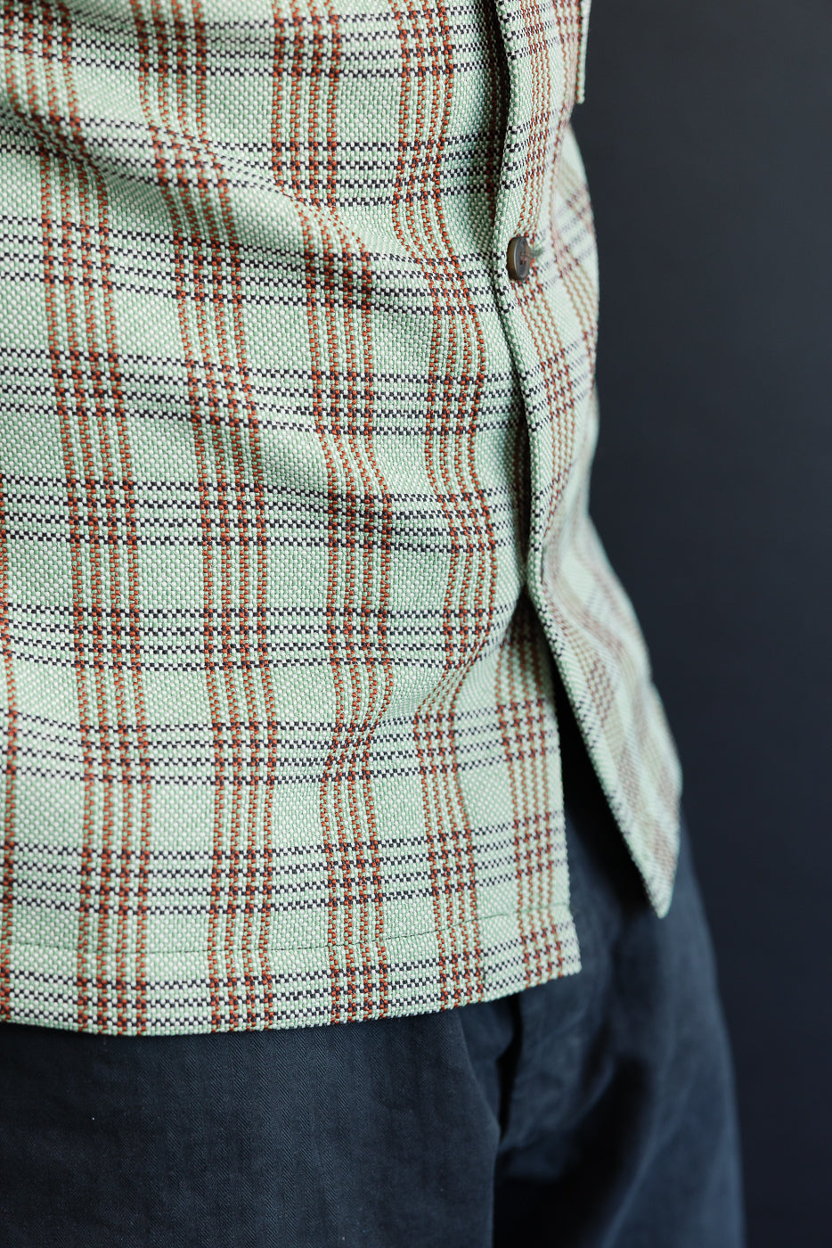 Close-up of front left side of green plaid lounge shirt with button, worn by 5'9