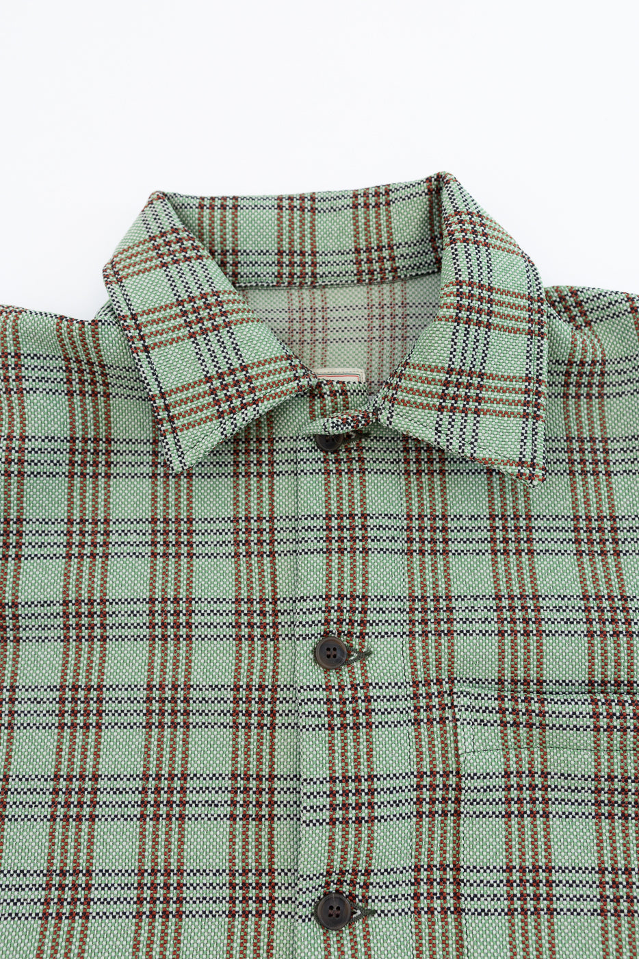 Close-up of front upper section of green plaid lounge shirt, showing collar, buttons, and textured fabric.