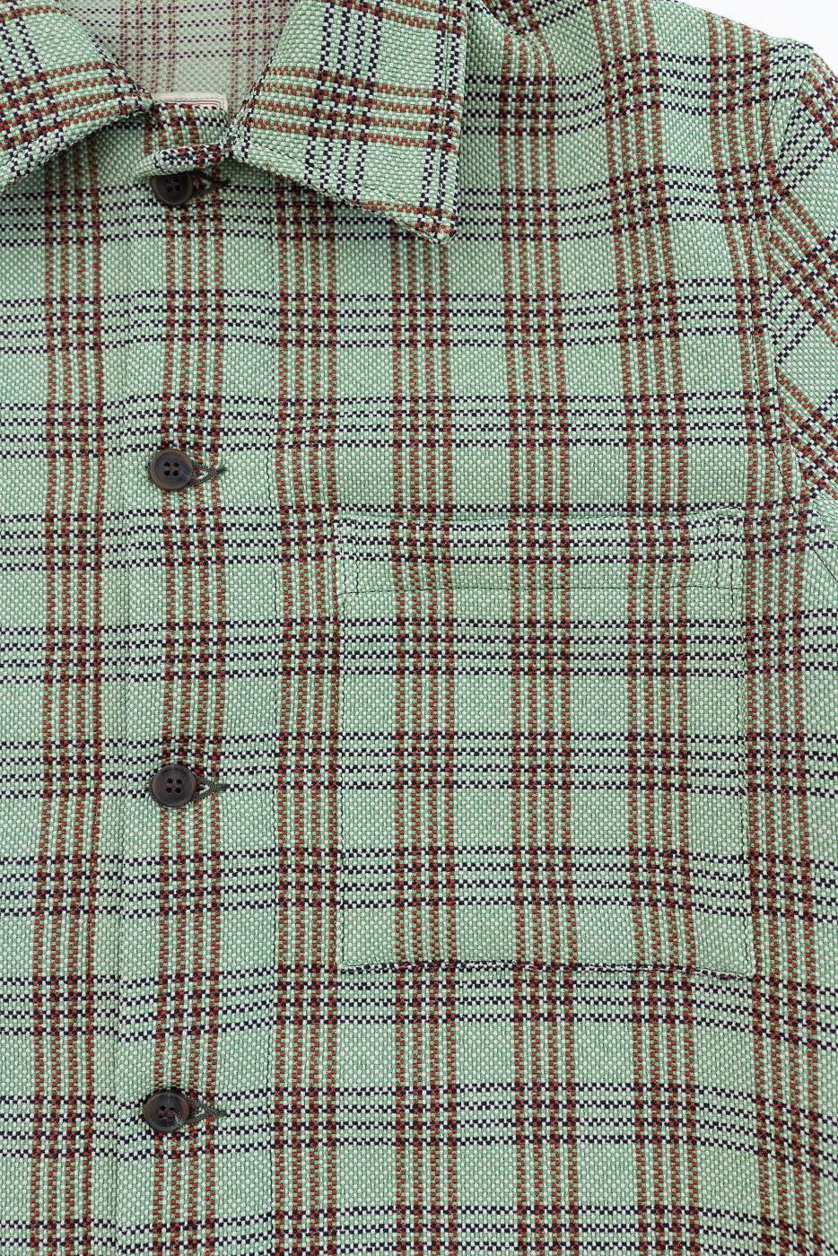 Close-up of front chest and collar of green plaid lounge shirt, showing plaid pattern, buttons, and textured fabric.